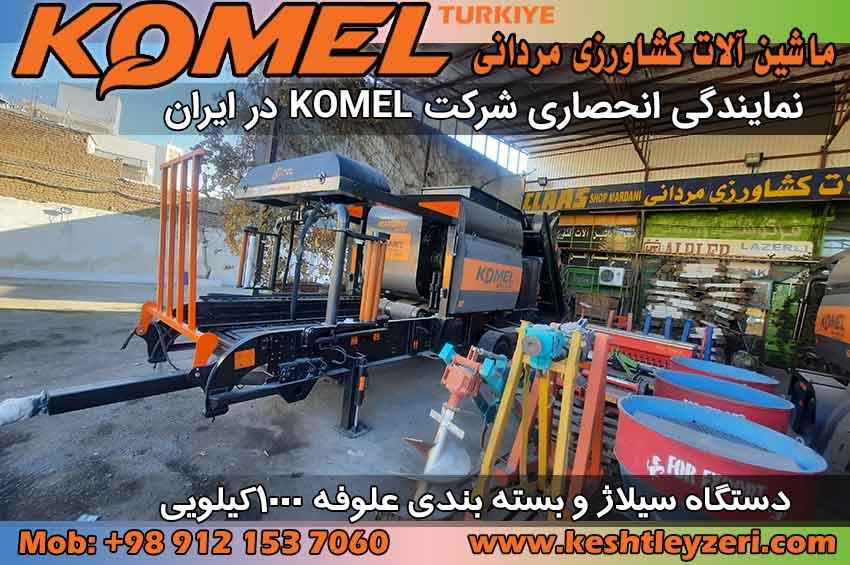 تصویر نشان‌دهنده دستگاه بسته‌بندی علوفه Komel است که در حال فشرده‌سازی و بسته‌بندی ذرت، یونجه و سایر